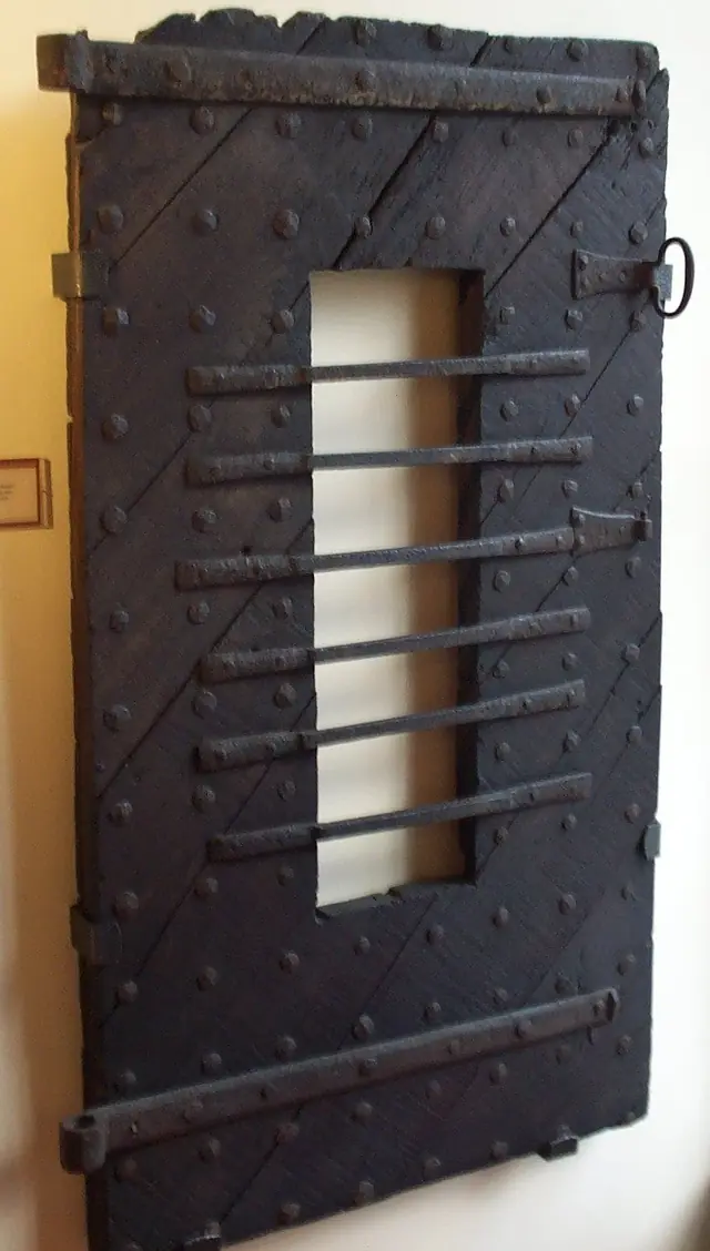 Simon Speed, a porta da antiga cadeia de Bedford, no John Bunyan Museum, foto, 2007 · Domínio público (`File:OldBedfordGaolDoor.JPG`; a atribuição da porta é do museu).