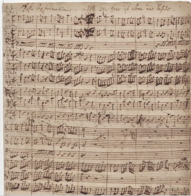 J. S. Bach (com C. P. E. Bach), autógrafo da cantata BWV 79, festa da Reforma de 1725 ("J. J. Festo Reformationis") · Bach Digital · Domínio público (`File:First page of autograph of cantata BWV 79 by J. S. Bach.jpg`). O Commons dá J. S. Bach e C. P. E. Bach como autores da folha.