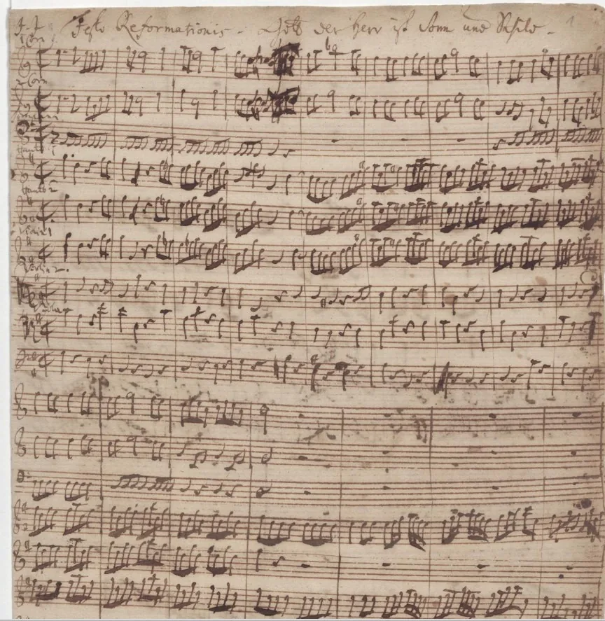J. S. Bach (com C. P. E. Bach), autógrafo da cantata BWV 79, festa da Reforma de 1725 ("J. J. Festo Reformationis") · Bach Digital · Domínio público (`File:First page of autograph of cantata BWV 79 by J. S. Bach.jpg`). O Commons dá J. S. Bach e C. P. E. Bach como autores da folha.